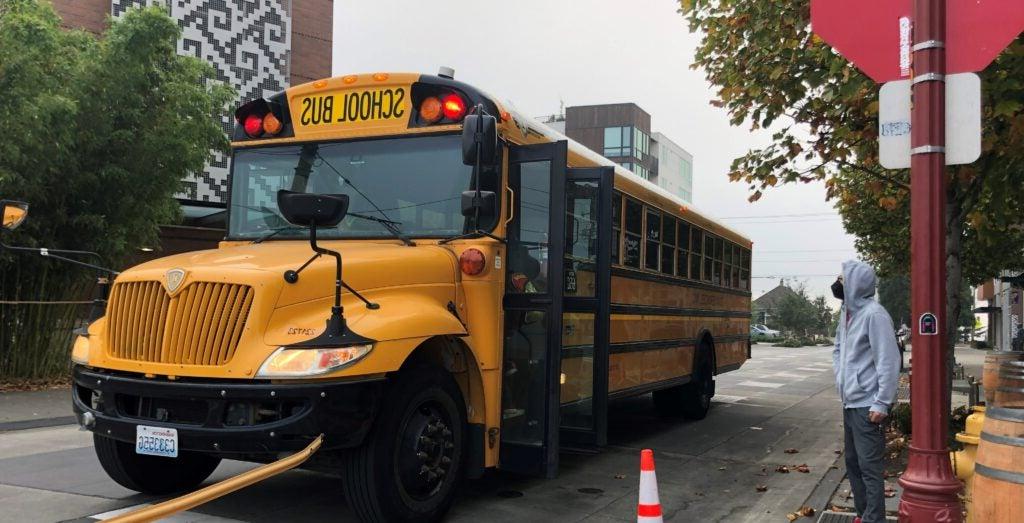 A parent watches at their student boards the school bus.